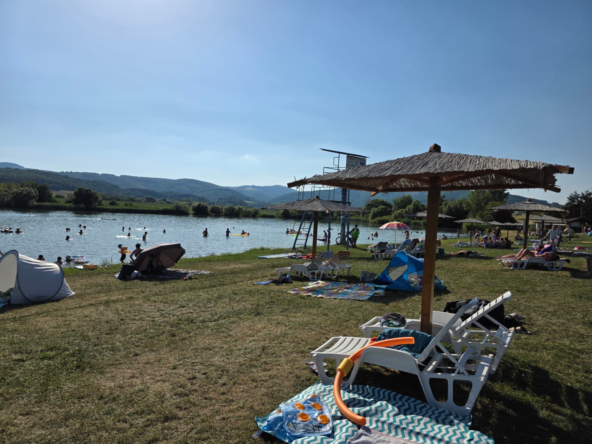 Kúpanie vo vodnej nádrži Ružiná so slamenými slnečníkmi a lehátkami