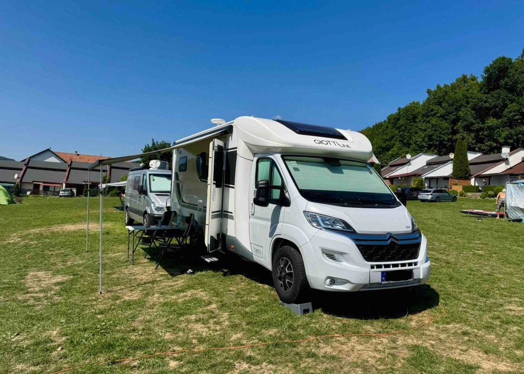 Karavan s predstanom na trávnatej parcele v autocampingu